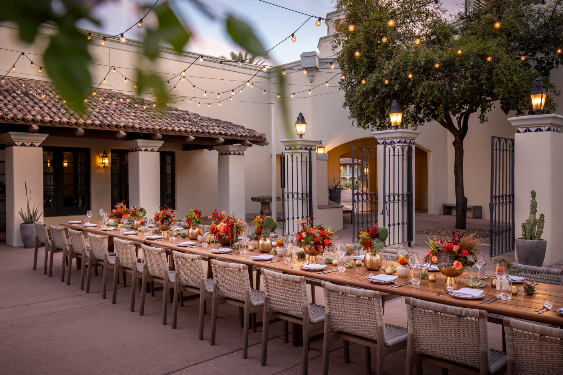 La Hacienda patio at dusk with string lights and a long dinner table at the Fairmont Scottsdale Princess